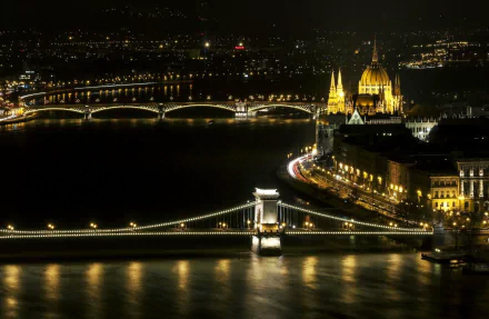 Night view of Budapest showcasing the illuminated Margaret Bridge and Chain Bridge over the Danube River, with the stunning architecture of the Parliament building in the background.