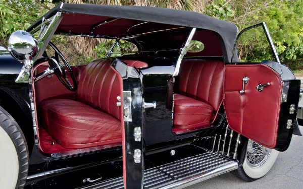 Classic vintage Duesenberg car with a black exterior and deep red leather interior, captured in high-definition for a sleek PC desktop wallpaper background.
