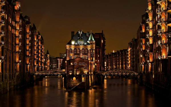 HD desktop wallpaper of Hamburg, Germany, featuring a nighttime view of illuminated historical buildings along a canal with bridges.