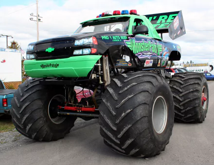 HD desktop wallpaper featuring a powerful monster truck with oversized tires, bright green and black design, and bold graphics, set against an outdoor backdrop.