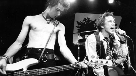 Black and white HD PC desktop wallpaper showing the Sex Pistols performing live, featuring the bassist playing and the vocalist singing into a microphone.