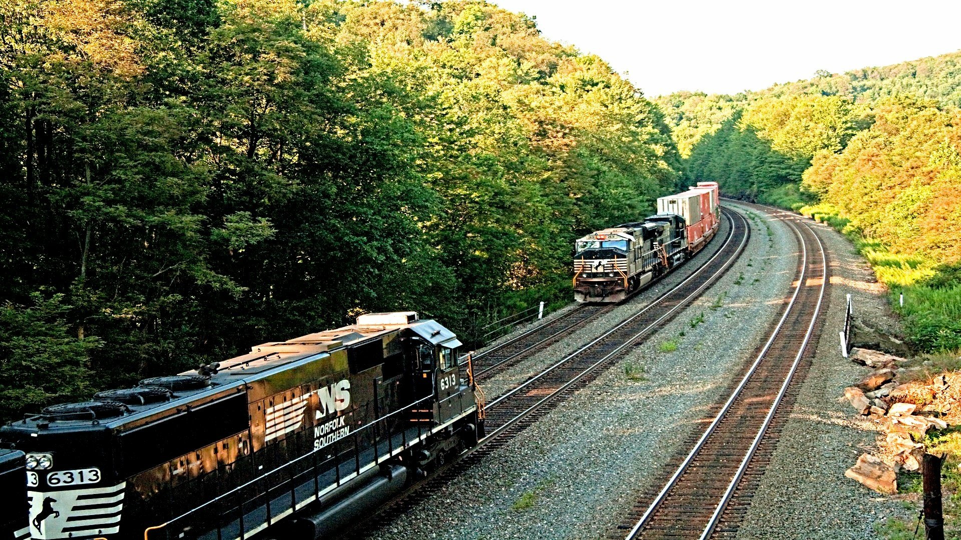 HD PC desktop wallpaper background: freight train (vehicle) pulling container cars along curved double tracks through lush green forest.
