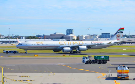 Passenger Airbus A340 aircraft with Etihad livery taxiing on the airport runway, shown in an HD desktop wallpaper and background quality image.