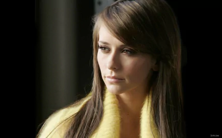 HD wallpaper featuring celebrity Jennifer Love Hewitt, showcasing her with long hair and a thoughtful expression, dressed in a yellow attire against a dark background.