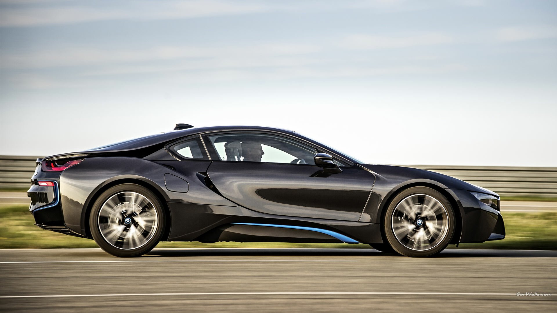 A sleek BMW i8 drives along a scenic road, captured in high definition. This dynamic image serves as an impressive desktop wallpaper and background.