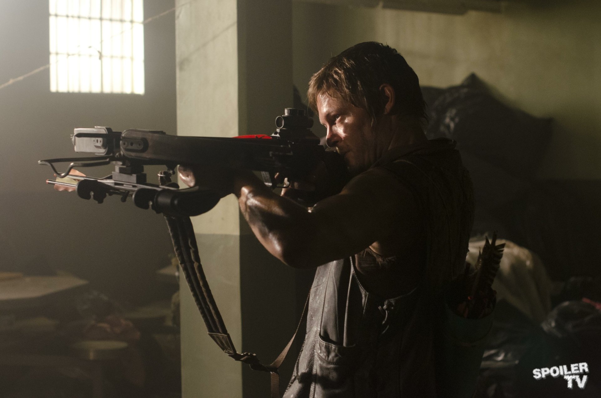 Daryl Dixon, played by Norman Reedus, aims a crossbow in a dimly lit scene from the TV show The Walking Dead, featured in an HD PC desktop wallpaper.
