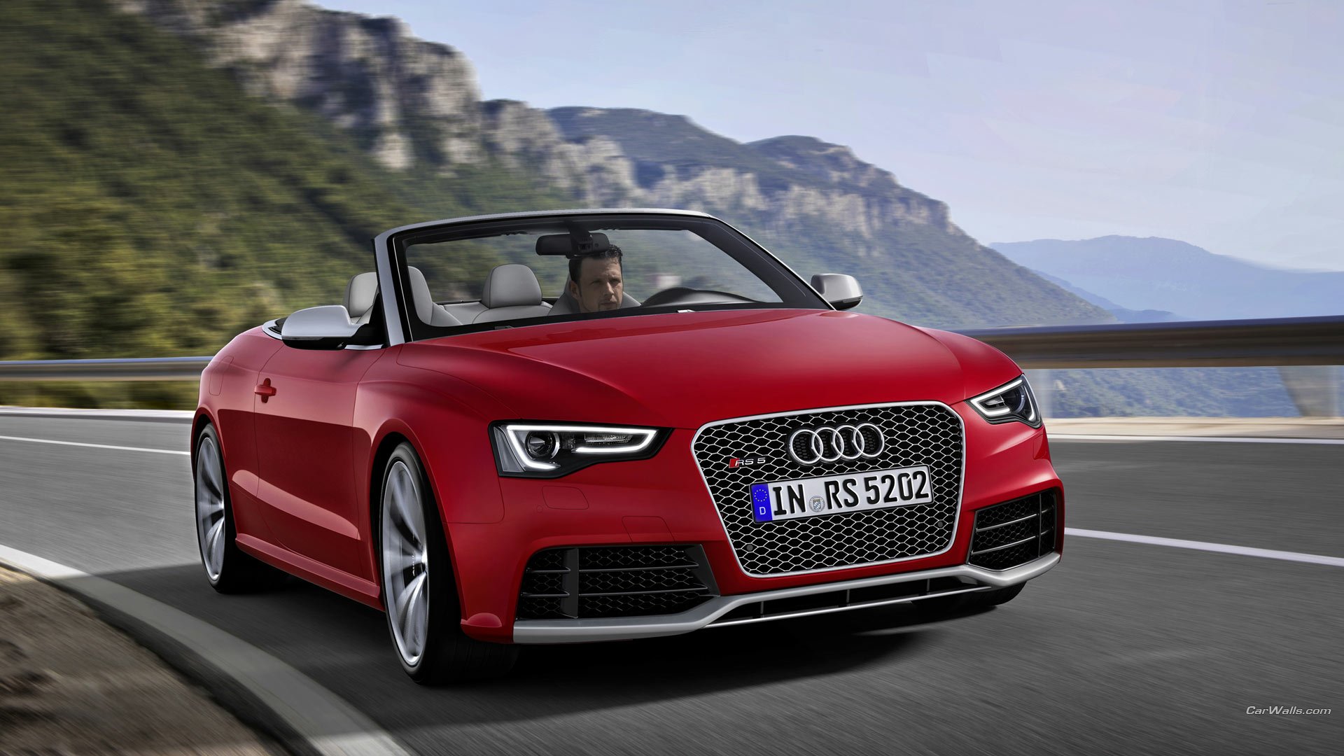 Red Audi RS5 convertible on a winding mountain road with cliffs and water in the background, presented as an HD PC desktop wallpaper and background.