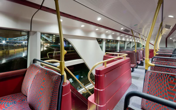 A spacious interior of a modern bus at night, featuring red-patterned seats and warm lighting, showcasing the vehicle's design for a vibrant HD PC desktop wallpaper.