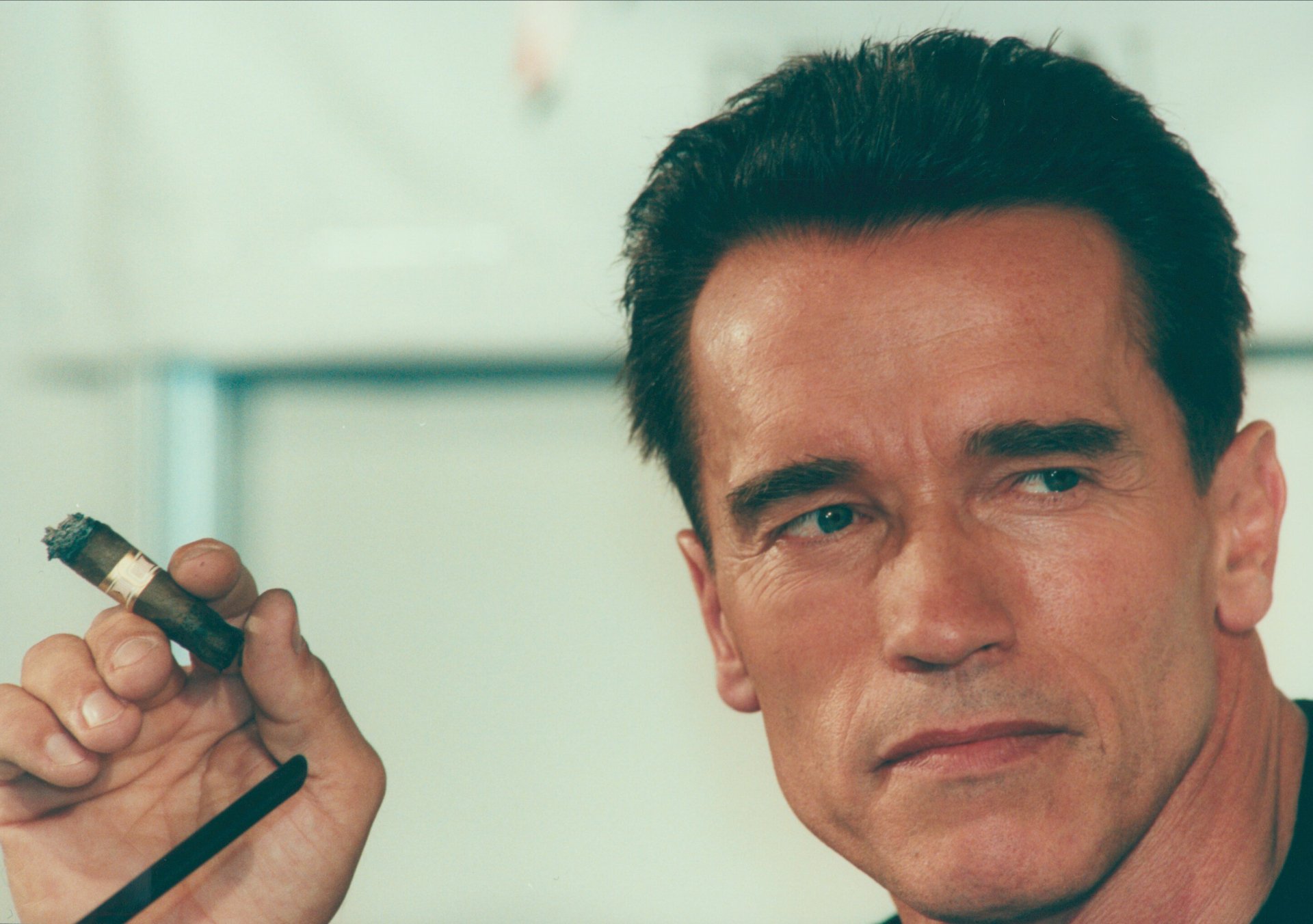 HD PC desktop wallpaper featuring a close-up portrait of celebrity Arnold Schwarzenegger holding a cigar with a focused expression.