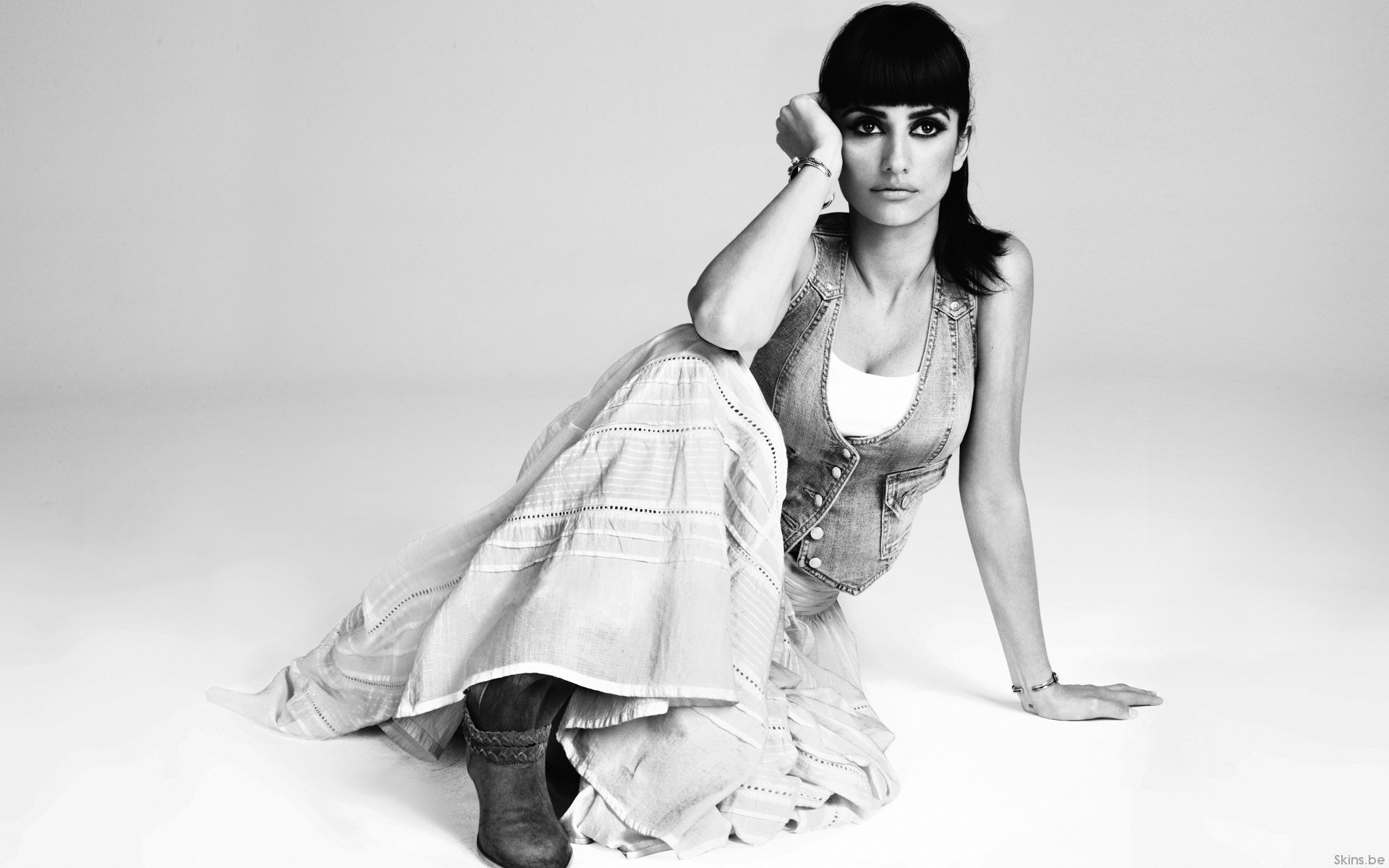 Black and white HD desktop wallpaper featuring celebrity Penelope Cruz seated on the floor with a contemplative expression and casual attire.