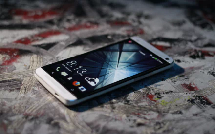 A sleek smartphone sits on a textured surface, showcasing its vibrant screen with abstract patterns, symbolizing the intersection of technology and design in this HD desktop wallpaper.