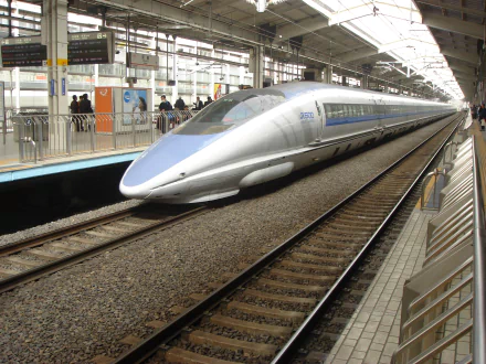 HD desktop wallpaper of a sleek silver bullet train on a Japanese railroad platform, showcasing modern rail transportation and high-speed vehicle design.