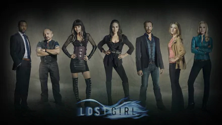 The image features a lineup of characters from the TV show Lost Girl, showcasing key figures against a dark background, with the show's title prominently displayed at the bottom.