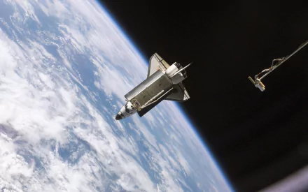 Space Shuttle Atlantis vehicle above Earth's curved blue cloud cover, HD PC desktop wallpaper background showing the orbiter and a robotic arm against the blackness of space.