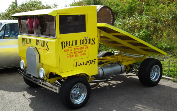 A vibrant yellow truck with a unique design, featuring a sloped cargo bed and vintage signage marking Beach Beers, Est. 1915. This HD wallpaper showcases a distinctive vehicle.