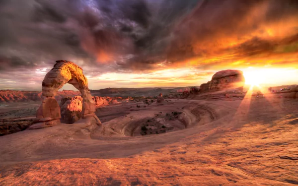 HD PC desktop wallpaper showcasing a dramatic canyon landscape at sunset, with a natural rock arch and vibrant skies highlighting the rugged terrain.