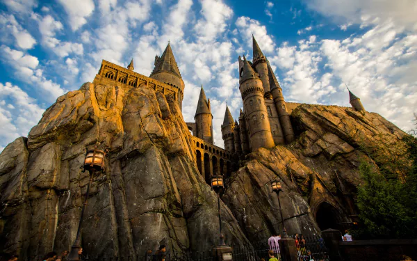 4K Ultra HD wallpaper showcasing the iconic Hogwarts castle from Islands of Adventure, perched on rugged rocks under a dramatic partly cloudy sky.