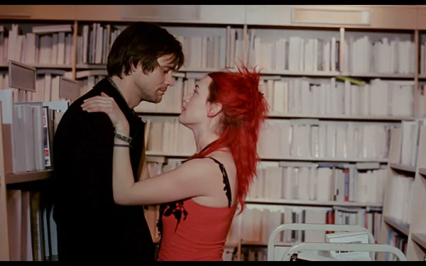 HD PC desktop wallpaper/background: movie still from Eternal Sunshine of the Spotless Mind — a red‑haired woman and a man embrace amid white library shelves, sharing an intimate look.