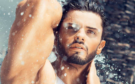 HD wallpaper featuring a handsome man in a striking pose, water droplets in the air around him, highlighting his strong features and wet hair.