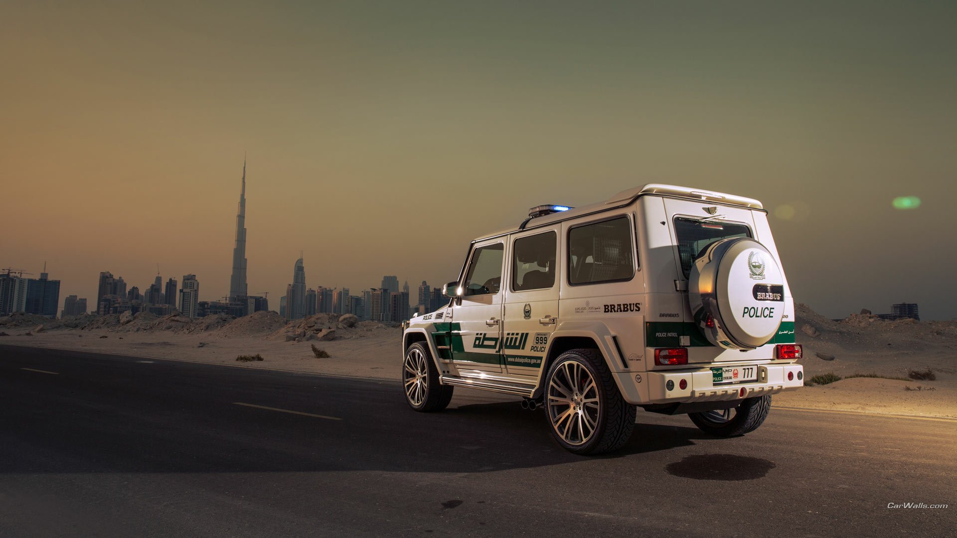 2013 Brabus B63S 700 Widestar Dubai Police Edition G63 parked on a desert road at dusk with the Dubai skyline (Burj Khalifa) — HD PC desktop wallpaper/background.