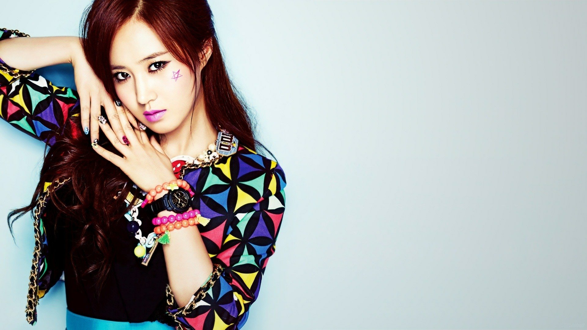 HD desktop wallpaper of a Korean woman with long hair, wearing colorful patterned clothing and bracelets, posing against a light, plain background.