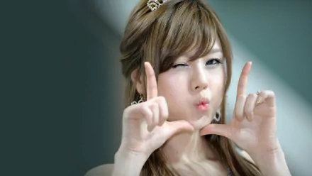 A woman of Korean descent playfully poses with her hands forming a frame, showcasing her cheerful expression in this HD desktop wallpaper background.