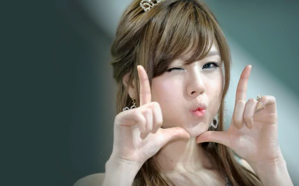 A woman of Korean descent playfully poses with her hands forming a frame, showcasing her cheerful expression in this HD desktop wallpaper background.