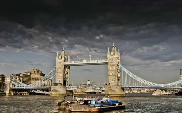4K Ultra HD image of London’s iconic man-made Tower Bridge spanning the River Thames under a dramatic cloudy sky.