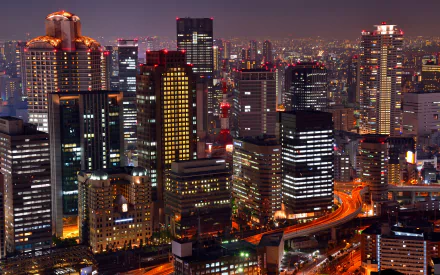A vibrant night view of Osaka's skyline, showcasing illuminated skyscrapers and bustling city streets, creating a dynamic urban landscape.