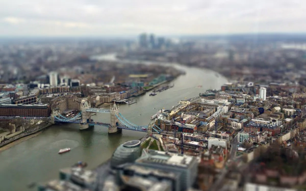 A stunning tilt-shift view of London's skyline features the iconic Tower Bridge above the River Thames, showcasing a miniature perspective of the city's vibrant landscape.