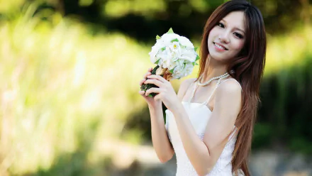 HD wallpaper featuring a smiling Korean woman in a white dress holding a bouquet of flowers, set against a blurred natural background.