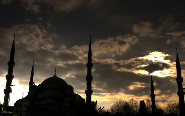 Silhouetted Sultan Ahmed Mosque with minarets against a dramatic cloudy sky in Istanbul, captured in a striking HD desktop wallpaper.