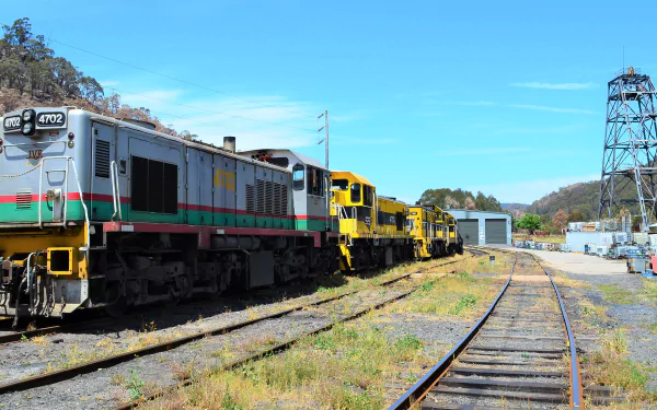 Lithgow train and locomotives, rail vehicles parked on sidings beside tracks under a bright blue sky — 2K Quad HD PC desktop wallpaper background.