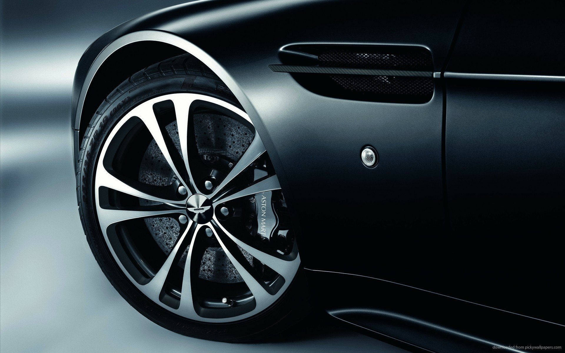 Close-up of a sleek black Aston Martin V12 Vantage wheel and side panel captured in high definition for a PC desktop wallpaper background.