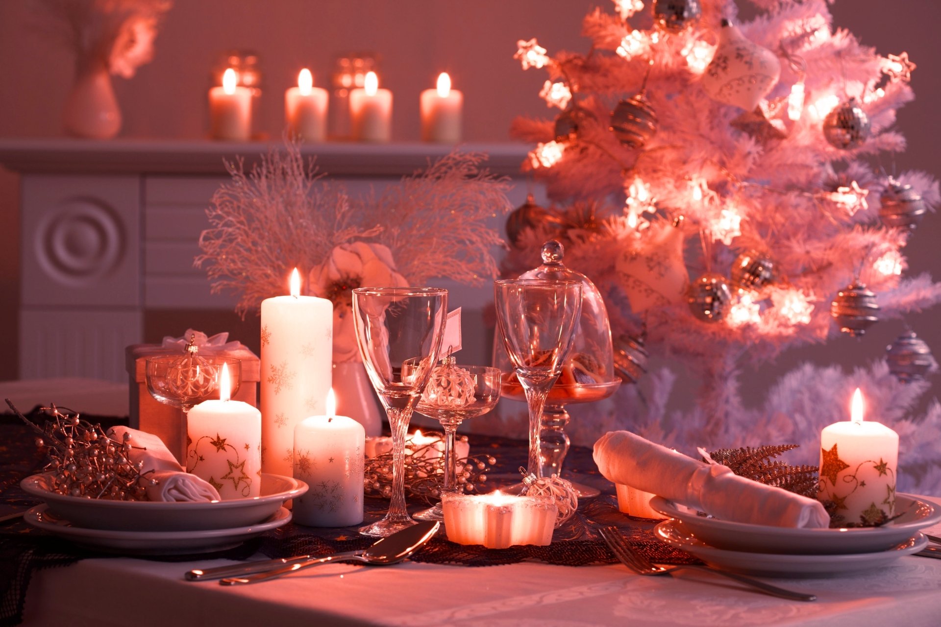 A cozy holiday scene featuring glowing candles, elegant glassware, and festive Christmas ornaments, set against a beautifully decorated tree, creating a warm atmosphere.