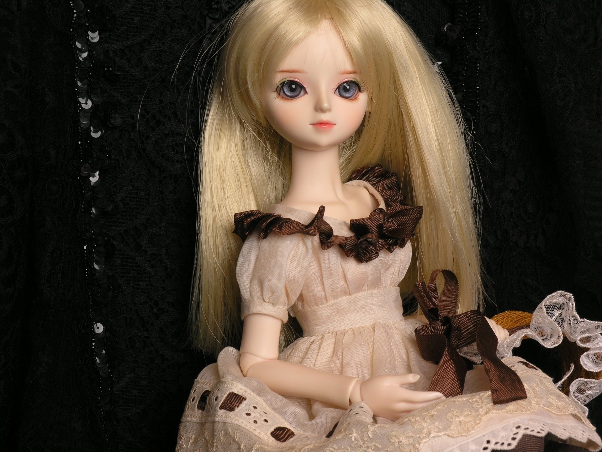 HD PC desktop wallpaper featuring a man-made doll with long blonde hair and a delicate cream dress adorned with brown ribbons against a dark, textured background.