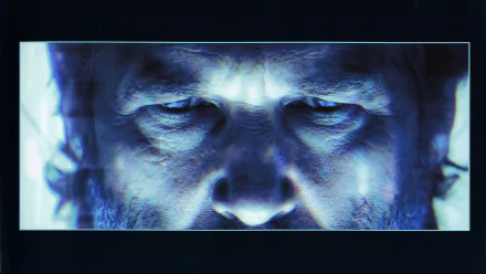 Close-up of a man's intense eyes illuminated in blue light, featured in a 4K Ultra HD PC desktop wallpaper inspired by the movie TRON: Legacy.