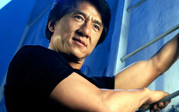 HD desktop wallpaper featuring Jackie Chan, showcasing his determined expression as he climbs a set of bars against a blue background.