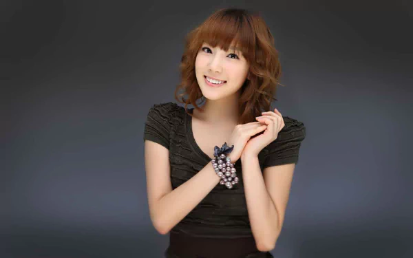 HD desktop wallpaper featuring Kim Tae-yeon, Korean singer and member of Girls' Generation (SNSD), smiling against a simple gray background.