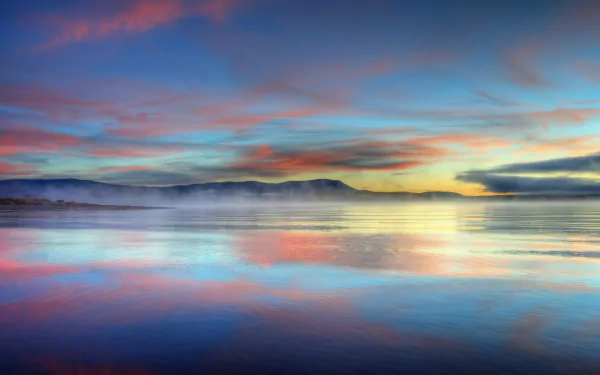 4K Ultra HD PC desktop wallpaper and background: serene ocean sunrise with vivid pastel sky reflections, misty distant coastline and calm water.