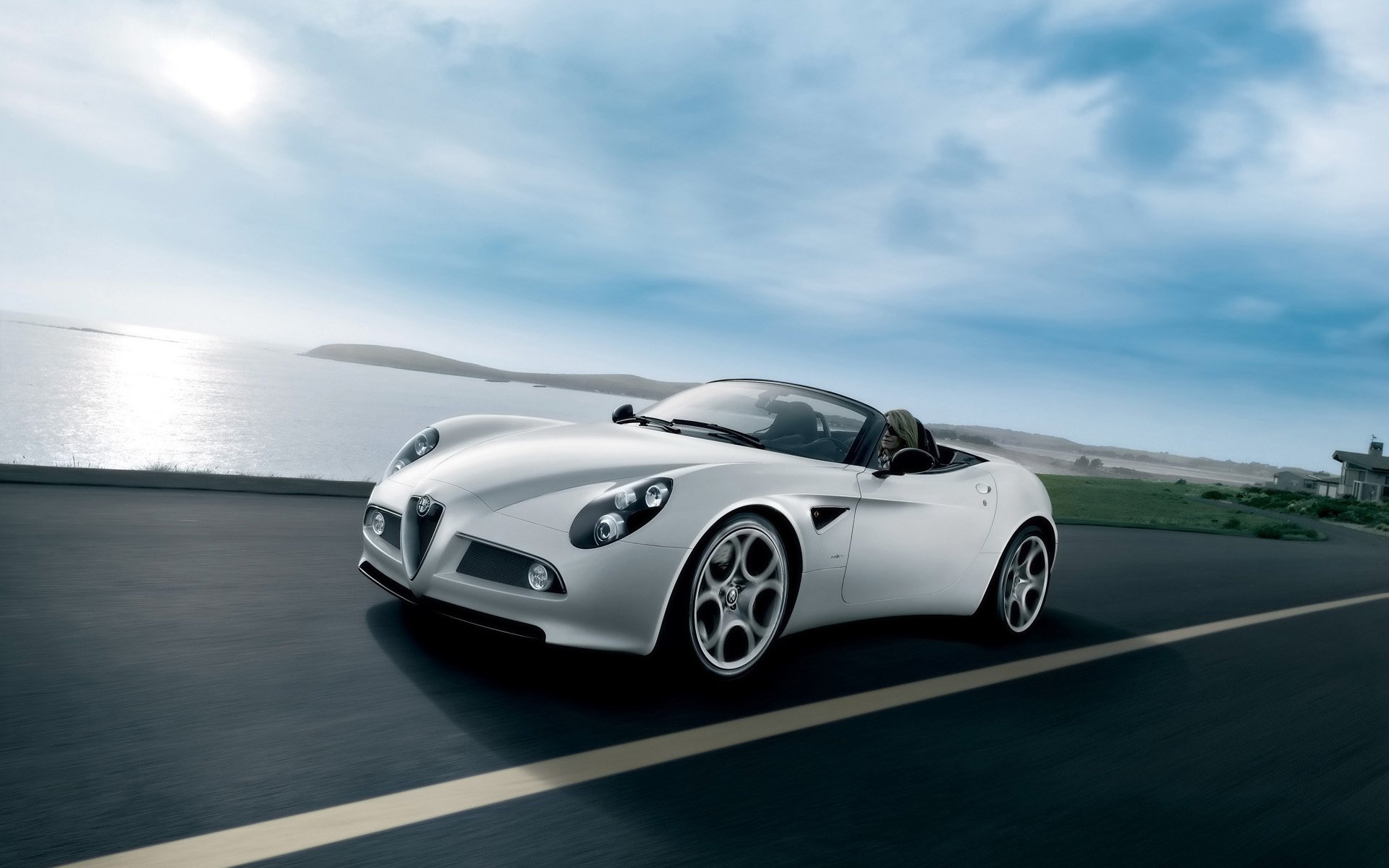 White Alfa Romeo 8C Spider vehicle on a coastal road under a blue sky — HD PC desktop wallpaper background.
