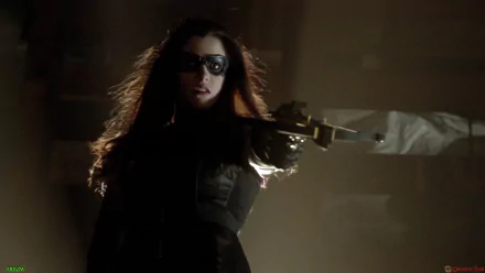 A dramatic HD wallpaper featuring the Huntress from the Arrow TV show, poised with a crossbow in a shadowy setting, exuding confidence and intensity.