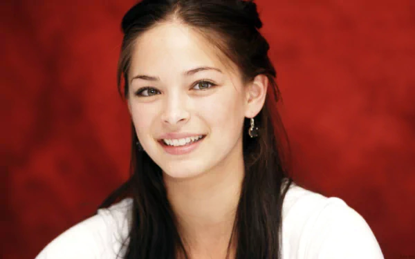 HD desktop wallpaper of Canadian actress and celebrity Kristin Kreuk smiling against a red background.