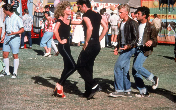 HD PC desktop wallpaper featuring a lively outdoor dance scene from the movie Grease, showcasing iconic characters in 1950s-style clothing.