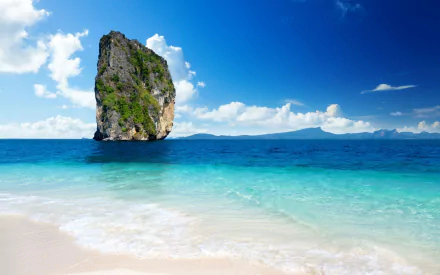 A stunning HD wallpaper showcasing a cliff rising from turquoise waters, framed by a clear blue sky and soft white sands, capturing the beauty of nature.