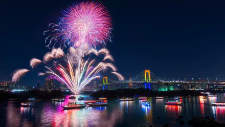 HD desktop wallpaper featuring vibrant fireworks over a river with illuminated boats and a brightly lit bridge at night.