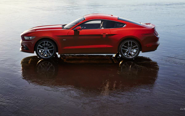 A striking 2015 Ford Mustang GT stands on a reflective surface, showcasing its sleek design and vibrant red color in this stunning HD desktop wallpaper.