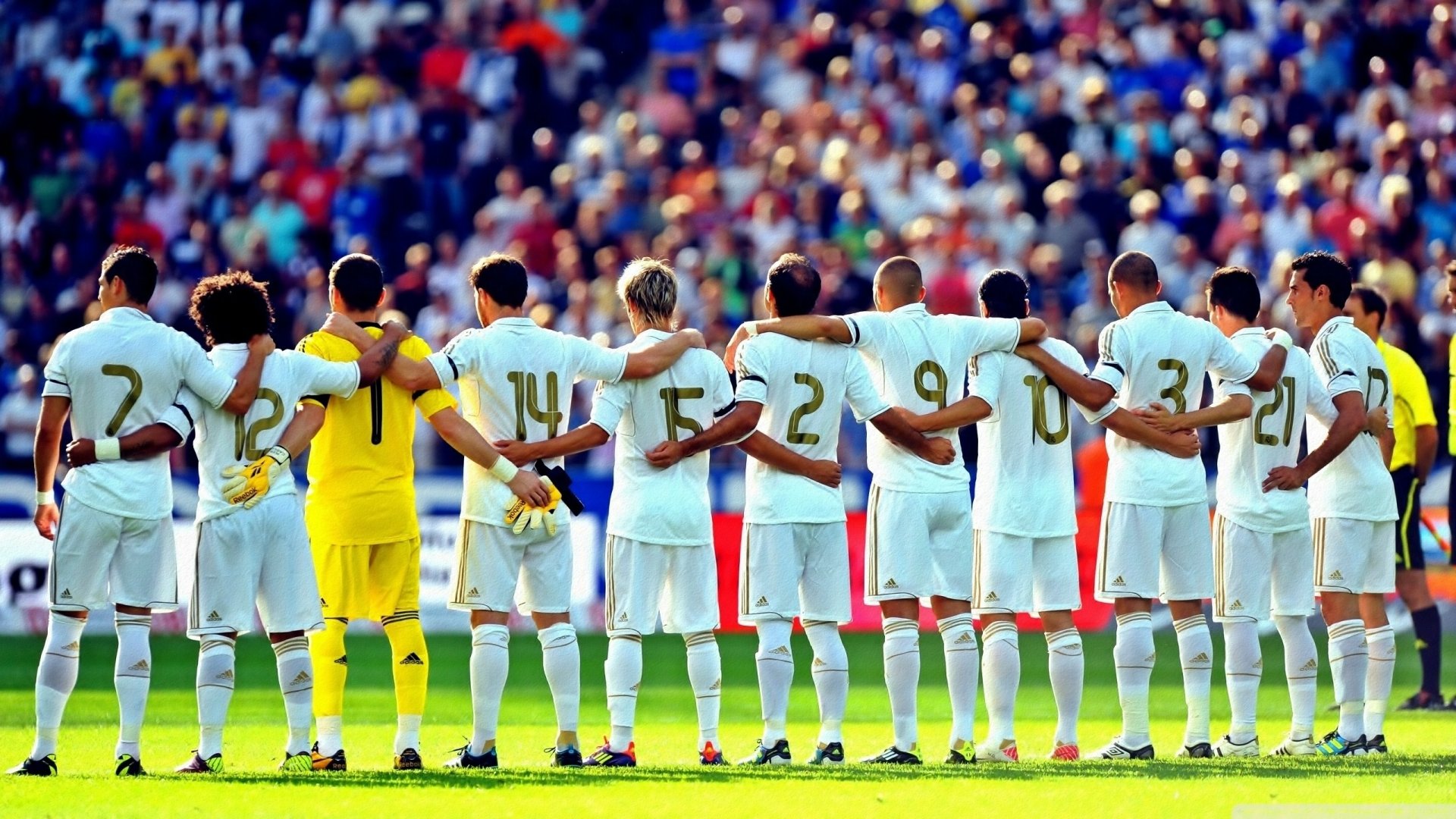 Real Madrid C.F. players stand united in a line on the field with their arms around each other. The image is a high-definition (HD) desktop wallpaper and background, highlighting sportsmanship.
