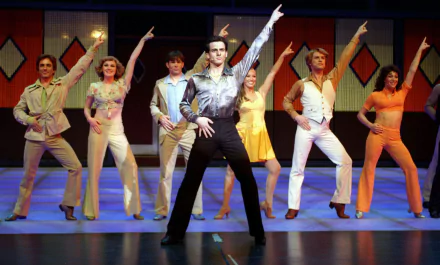 Cast of Saturday Night Fever: The Musical performing a choreographed dance number, with vibrant stage lighting, featured in a HD PC desktop wallpaper background.