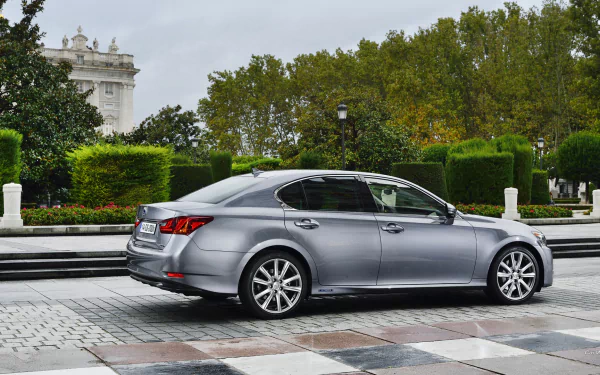 HD PC desktop wallpaper featuring a sleek silver Lexus GS 300h parked on a city street with greenery and classical architecture in the background.